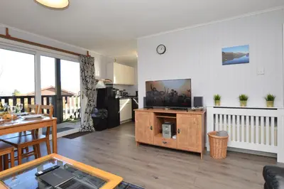 a living room with a television and a table at Holy Loch Lodge in Hunters Quay