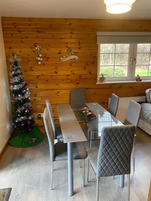 a dining room with a christmas tree and a table and chairs at La Fortuna Lodges in Stirling