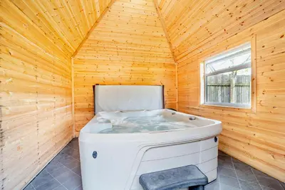 a large white tub in a wooden room with a window at La Fortuna Lodges in Stirling