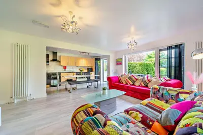 a living room with a red couch and a table at La Fortuna Lodges in Stirling
