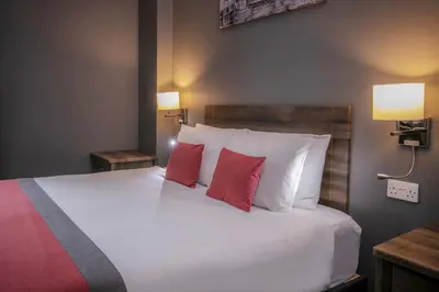 a bedroom with a large bed with two red pillows at Best Western Glasgow Hotel in Glasgow