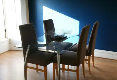 a glass table with chairs and a laptop on it at Dreamhouse Apartments Glasgow West End in Glasgow