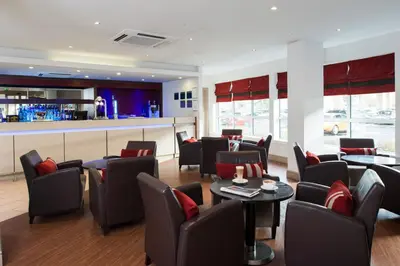 a restaurant with chairs and tables and a bar at Holiday Inn Express - Glasgow Airport by IHG in Paisley
