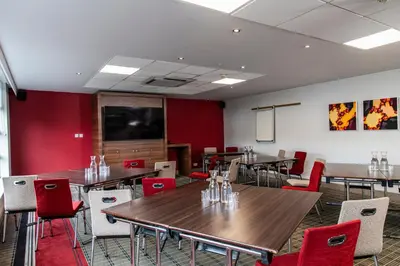 a dining room with tables and chairs and a screen at Holiday Inn Express - Glasgow Airport by IHG in Paisley