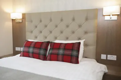 a bed with two red pillows in a hotel room at Ambassador Hotel in Glasgow