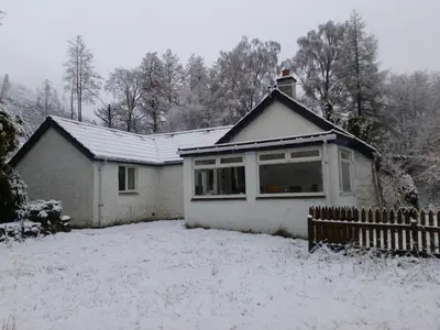 a house with snow on the roof of it at Craignavie Cottage in Killin
