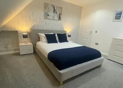 a bedroom with a large bed with blue pillows at Alma Villa in Falkirk
