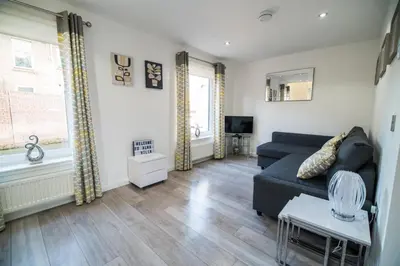 a living room with a couch and a tv at Alma Villa in Falkirk