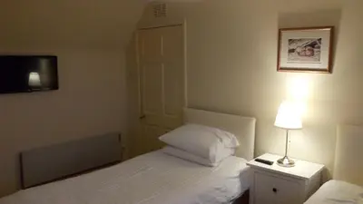 a bedroom with two beds and a lamp and a door at Feochan View in Oban