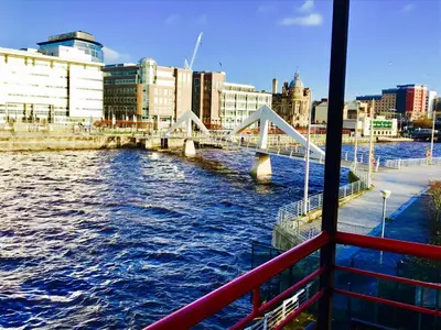 a boat on a river with a bridge at Glasgow City Centre Flat with River Views and Parking in Glasgow