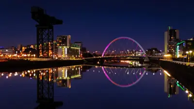 a city skyline with a bridge at night at Glasgow City Centre Flat with River Views and Parking in Glasgow