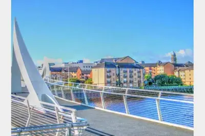 a bridge over a river with buildings in the background at Glasgow City Centre Flat with River Views and Parking in Glasgow