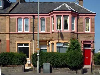 a pink house with a red door on a street at Badjao B&B in Edinburgh