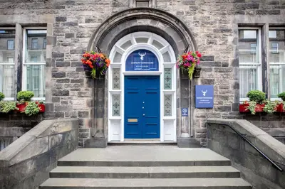 a blue door on a brick building with flowers at Leonardo Edinburgh City in Edinburgh