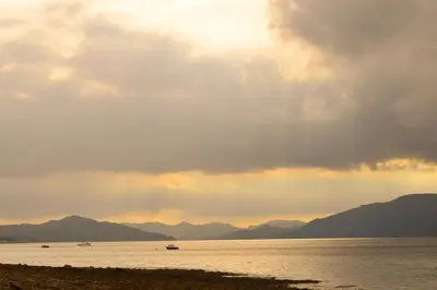 a cloudy sky over the water with boats in it at Springburn Cottage in Strachur