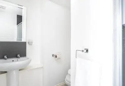 a white bathroom with a sink and a mirror at Kelpies Serviced Apartments in Falkirk