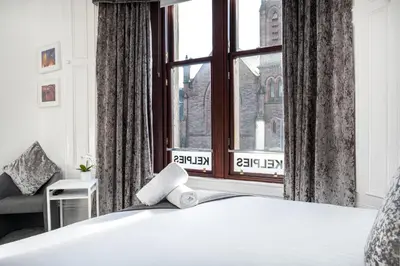 a bedroom with a bed and a large window at Kelpies Serviced Apartments in Falkirk