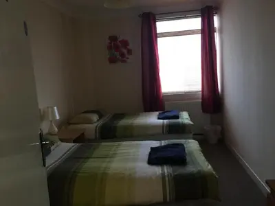 a hotel room with two beds and a window at Laughing Buddha Guesthouse in Uddingston