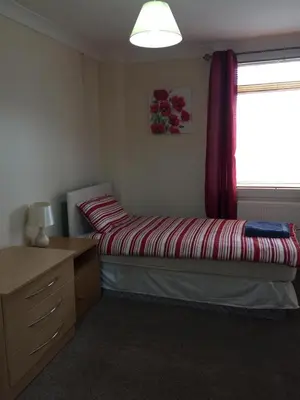 a small bedroom with a bed and a window at Laughing Buddha Guesthouse in Uddingston