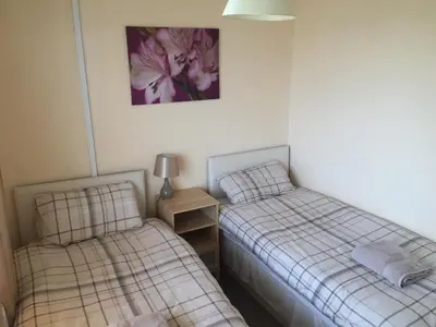 two beds in a bedroom with a picture on the wall at Laughing Buddha Guesthouse in Uddingston