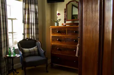 a bedroom with a dresser and a chair and a mirror at Glenegedale House in Kintra