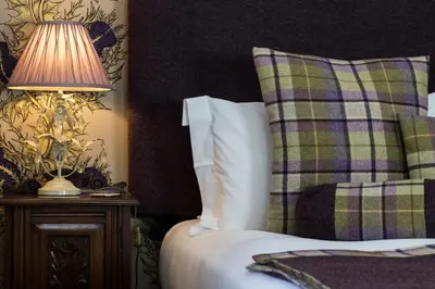a bedroom with a bed with a lamp on a table at Glenegedale House in Kintra