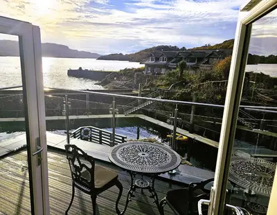 a balcony with a table and chairs and a view of the water at Melfort Pier & Harbour Resort in Kilmelford