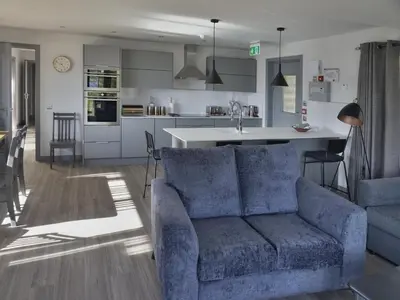 a living room with a blue couch and a kitchen at Melfort Pier & Harbour Resort in Kilmelford