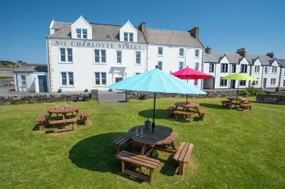 a table with a blue umbrella in front of a building at No. 1 Charlotte Street in Port Ellen