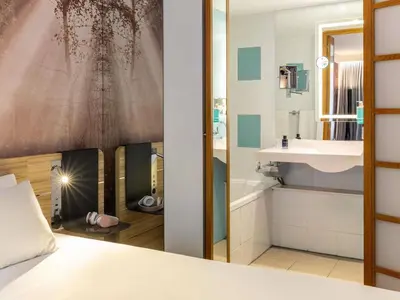 a bathroom with a bed and a sink and a mirror at Novotel Edinburgh Centre in Edinburgh