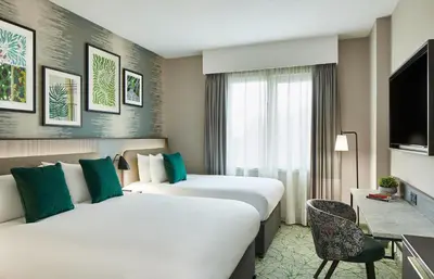 a hotel room with two beds and a tv at Leonardo Royal Hotel Glasgow in Glasgow
