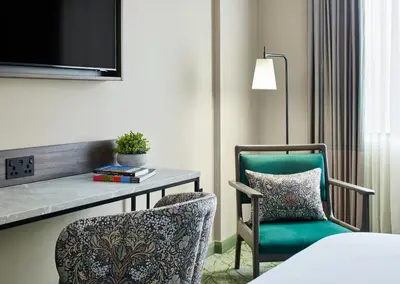 a hotel room with a desk and a chair and a table at Leonardo Royal Hotel Glasgow in Glasgow