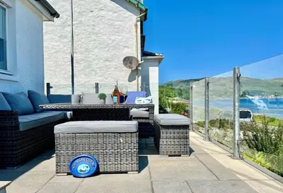 a patio with a table and chairs and a view of the ocean at Craignethan in Kames
