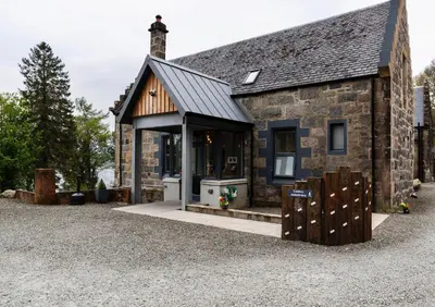 a stone house with a black roof at Ben Cruachan Inn - Restaurant, Pub with Rooms in Loch Awe
