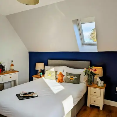 a bedroom with a large white bed with a blue wall at Ben Cruachan Inn - Restaurant, Pub with Rooms in Loch Awe