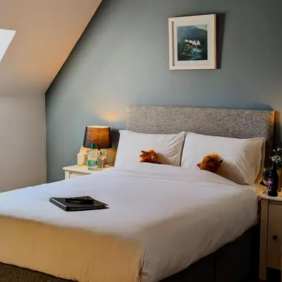 a bedroom with a bed with two dogs sitting on it at Ben Cruachan Inn - Restaurant, Pub with Rooms in Loch Awe