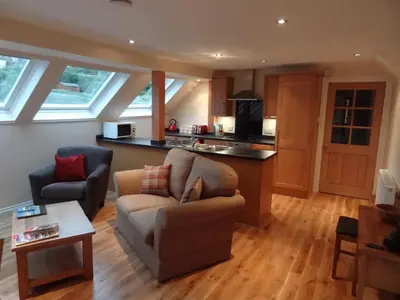 a living room with a couch and a kitchen at Coach House at The Glen in Helensburgh