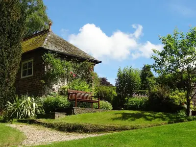 a bench in a garden next to a building at Coach House at The Glen in Helensburgh