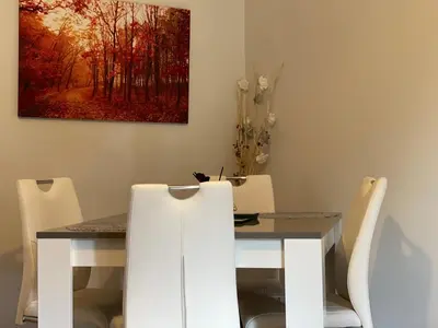 a dining room table and chairs with a painting on the wall at King Court Apartment in Motherwell