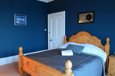 a bedroom with a wooden bed with blue walls at Briar Brae Bed & Breakfast in Stranraer