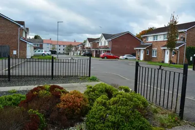 a wrought iron fence in a residential street with houses at Glasgow Hampden House in Glasgow