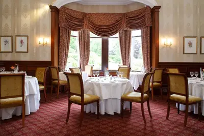 a dining room with white tables and chairs and a window at Garvock House Hotel in Dunfermline