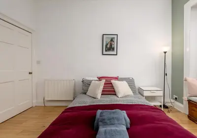 a bedroom with a large bed with red blanket at The Lothian Road Residence in Edinburgh