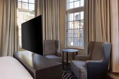 a hotel room with a flat screen tv and two chairs at Doubletree by Hilton Edinburgh City Centre in Edinburgh