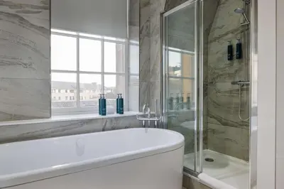 a bathroom with a tub and a shower and a window at Doubletree by Hilton Edinburgh City Centre in Edinburgh