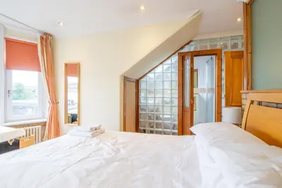 a large white bed in a room with a window at Almada Apartment in Hamilton