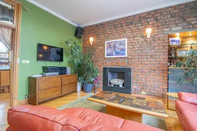 a living room with a couch and a brick wall at Almada Apartment in Hamilton