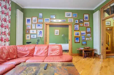 a living room with a red couch and a wall of pictures at Almada Apartment in Hamilton