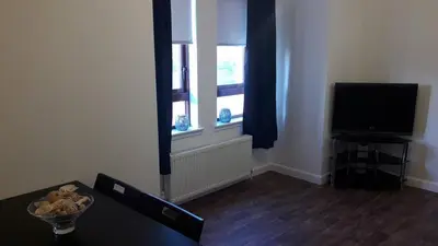 a living room with a table and a television at Sunnyside Apartments in Coatbridge