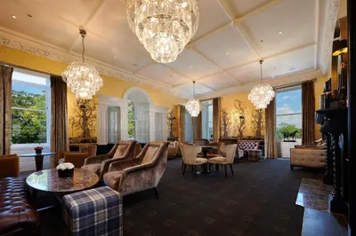a large living room with chandeliers and chairs and tables at Cameron House on Loch Lomond in Balloch